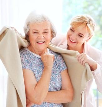 caregiver covering senior woman with plaid