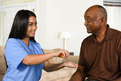 health care worker helping an elderly patient take his pills