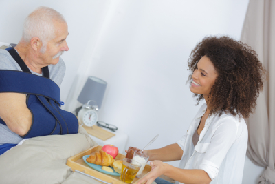 caregiver bringing food to senior man smiling