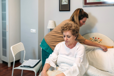 Female caregiver accommodating the pillow to elderly female patient